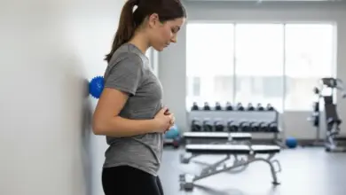 Žena se protahuje u zdi v posilovně pro úlevu od bolesti.