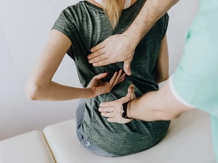 Fyzikální terapeut upravuje bederní páteř pacientovi při bolesti.