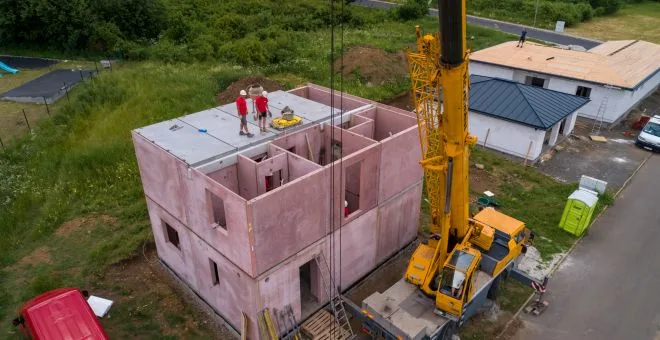 Dvěpatrový dům z keramického betonu ve fázi hrubé stavby s žlutým kranem.