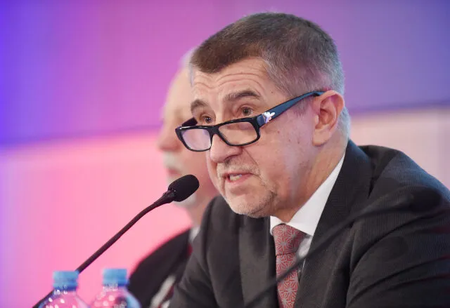 Muž v obleku mluví do mikrofonu na konferenci.