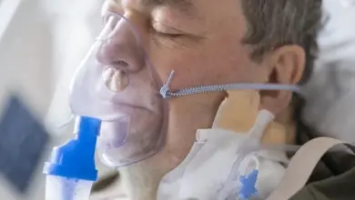 Muž v nemocnici dýchá kyslík přes obličejovou masku.