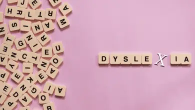 Slovníkové kostky s písmeny tvořící slovo dyslexie na růžovém pozadí.