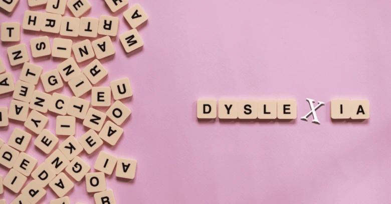 Slovníkové kostky s písmeny tvořící slovo dyslexie na růžovém pozadí.