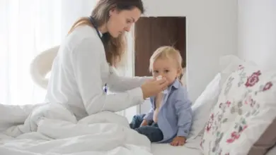 Lékařka vyšetřuje hrdlo dítěte v posteli.