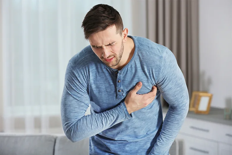 Muž drží ruku na hrudi v bolesti.