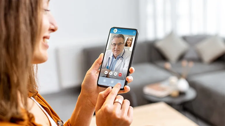Žena telefonuje s lékařem pomocí mobilního telefonu.