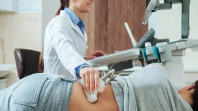 Lékař provádí ultrazvukové vyšetření pacientovi na zádech.