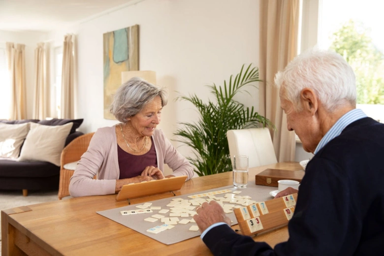 Dvojice seniorů hraje společně hru v obývacím pokoji.