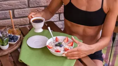 Žena snědá ovesnou kaši s ovocem a kávou venku.