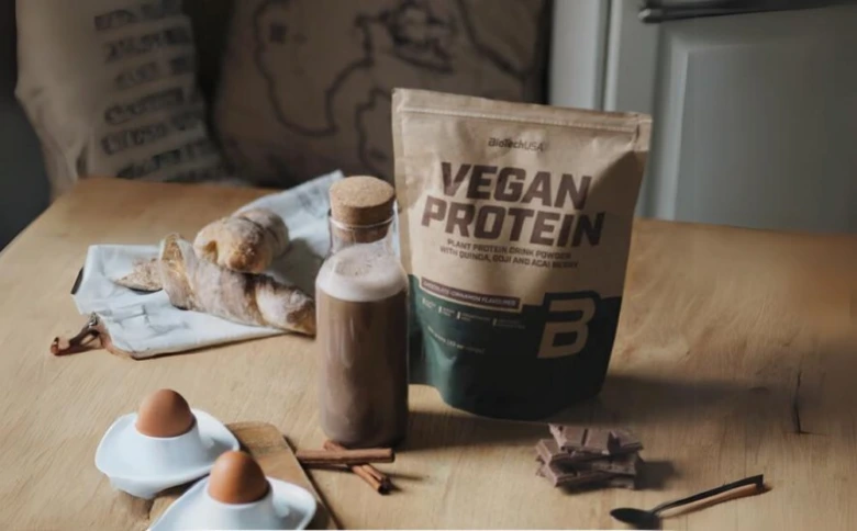 Veganský bílkovinový prášek s nápojem na dřevěném stole.