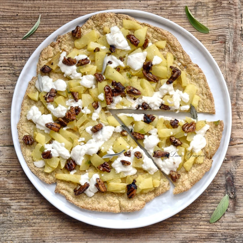 Nízkosacharidová pizza s ovocem a ořechy na bílém talíři.