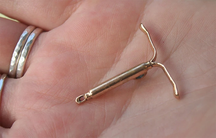 Zlaté nehormonální nitroděložní tělísko GyneFix v ruce