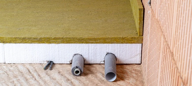 Detailní pohled na kročejovou izolaci s průchody pro potrubí.