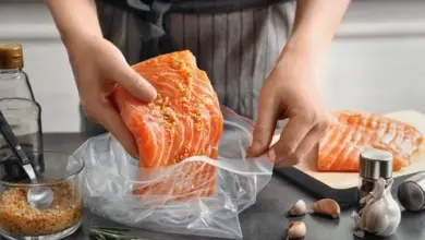 Osobě se připravuje losos s kořením v plastovém pytlíku.