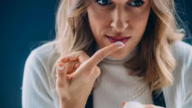 Žena nanáší krém na rty pro péči o opar.