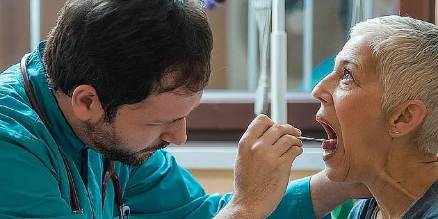 Lékař zkoumá hrdlo pacientky pomocí nástroje.