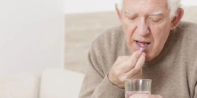 Elderly man taking pill