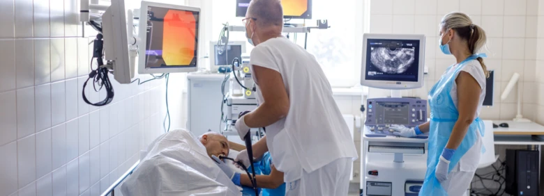 Lékaři provádějí ultrazvukové vyšetření slinivky břišní pacientovi v nemocničním prostředí.