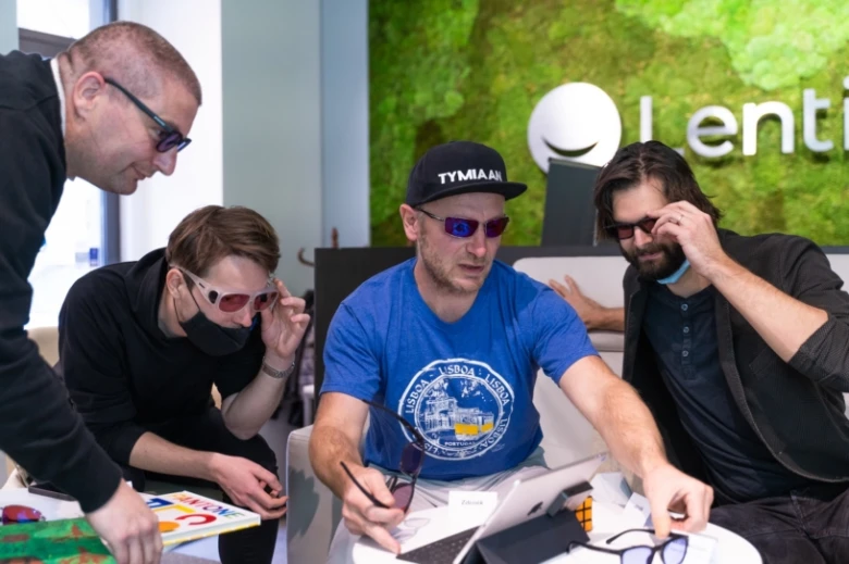 Muži zkoušejí brýle pro barvoslepé v kancelářském prostředí.