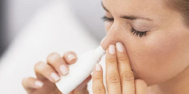Žena používá nosní sprej pro léčbu alergií na prachové roztoče.