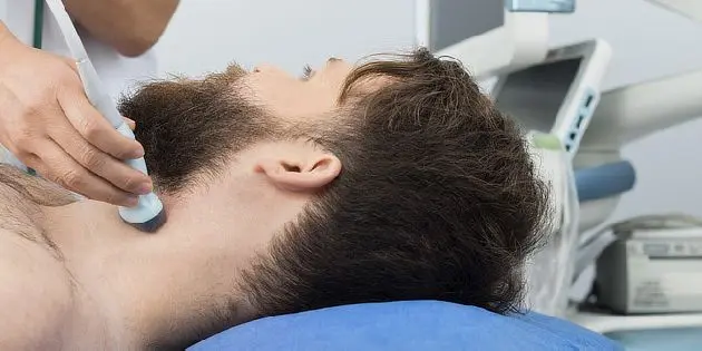 Lékař provádí ultrazvukové vyšetření krku pacienta v ordinaci.