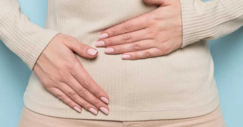 Žena drží ruce na břiše, symbolizující menstruační cyklus.