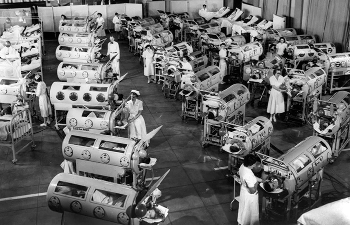 Historická fotografie dětí v inkubátorech s ošetřovatelkami.