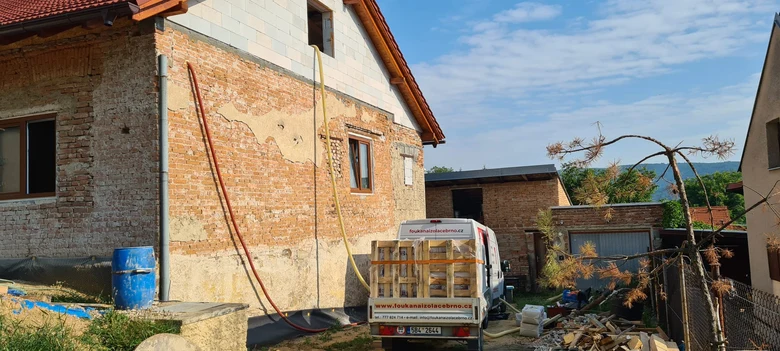 Dům v rekonstrukci s viditelnou stříkanou izolací na zdi.