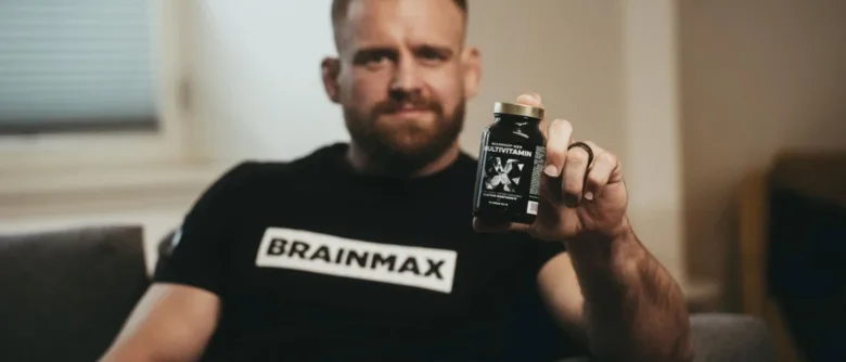 Muž drží v ruce lahvičku s multivitamíny.