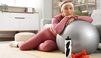 Žena cvičí na velkém fitbalu pro prevenci bolesti zad.