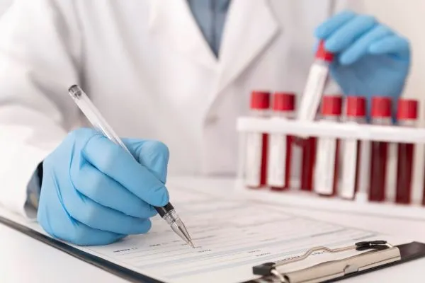 Lékař zapisuje výsledky krevních vzorků pro diagnostiku.