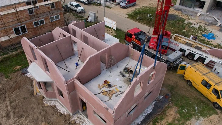 Nezhotovený dům z keramického betonu na staveništi s výškovým jeřábem.